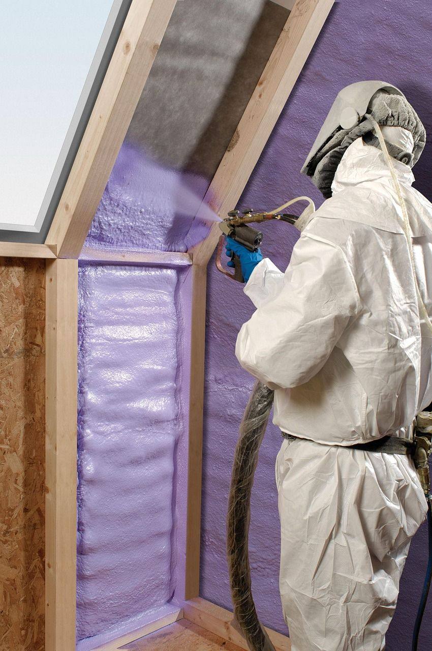 Installer spraying expanding foam insulation into wall cavities